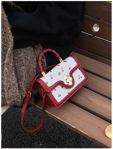 Close-up of retro cherry print small square bag with twisted handle and flower lock