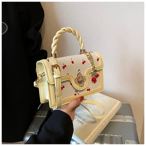 Detail of cherry print handbag with twisted handle and golden flower twist lock