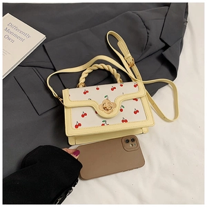 Detail of cherry print handbag with woven handle and gold flower twist lock closure