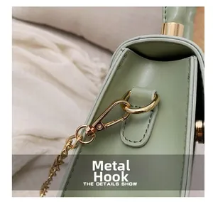 Close-up of golden metal hooks and chain on a light green textured leather handbag