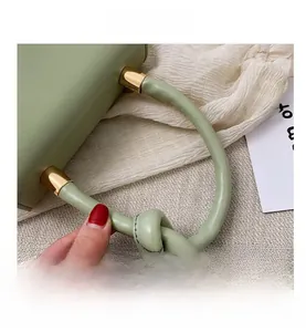 Close-up of light green PU leather handbag with gold metal hardware and knot handle detail