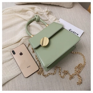 Detail view of light green PU leather handbag with gold buckle and twisted handle