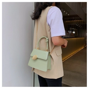 Mint green PU leather crossbody bag with knot handle and gold chain worn by a model