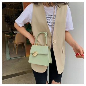 Close-up of mint green PU handbag featuring knot handle and golden metal clasp lock