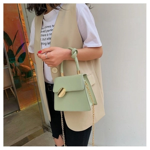 Detail of sage green leather handbag with gold round lock and elegant knotted handle