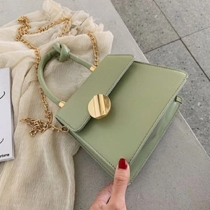 Detail of pea green PU leather handbag with gold chain strap and metal twist lock closure