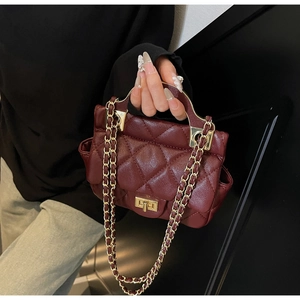 Detailed shot of burgundy quilted texture and gold metal handle on chain bag