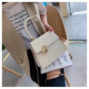 Detail of a creamy white PU leather handbag featuring a round knotted handle and gold clasp