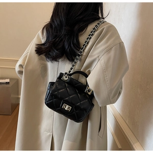Close-up of quilted black leather bag with silver chain strap and metallic handle detail
