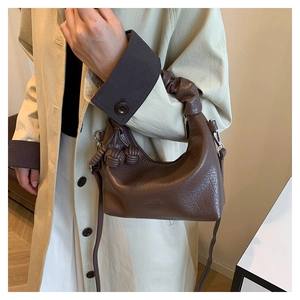 Detail of dark brown leather crescent bag with ruched cloud handle and knot charm detail