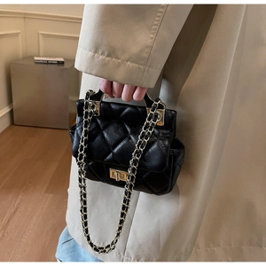 Detailed close-up of quilted black leather bag with gold twist lock and chain strap