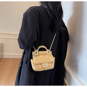 Detail of quilted apricot mini bag featuring a silver twist lock and chain strap