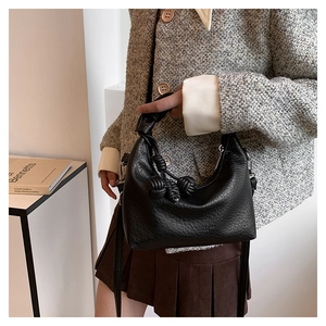 Detail of black pebbled leather crescent bag with unique knot handle and crossbody strap