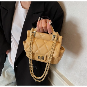 Detail of quilted leather handbag featuring a golden metal turn-lock and chain strap