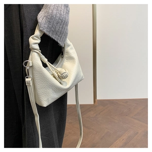 Detail of off-white lychee texture handbag with decorative knot and metal D-ring side