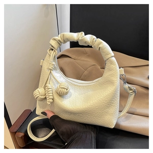 Detail of cream lychee texture bag featuring ruched handles and knot accents