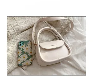 Compact cream leather handbag detail showing small size compared to a mobile phone
