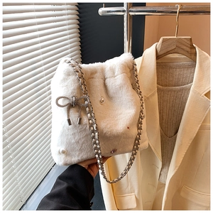 Détail du sac seau en fausse fourrure blanche avec perles et breloques de nœuds métalliques