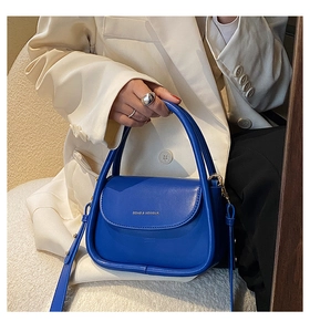 Detail of royal blue leather crossbody bag with top handle and gold logo hardware