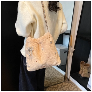 Détail du sac à bandoulière en peluche abricot avec perles et nœud scintillant sur modèle