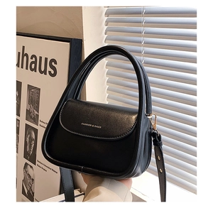 Detailed view of black U-shaped leather handbag with gold metal hooks and logo text