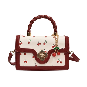 White cherry print handbag with red woven handle and gold flower twist lock