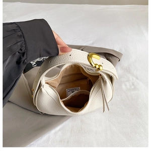 Detail view of the beige lychee texture leather bag interior with golden metal hardware