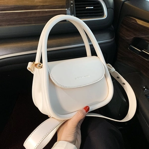 White mini PU leather saddle bag with wide strap shown in car interior setting