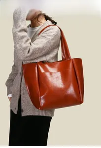 Dettaglio della borsa tote in pelle marrone con grande tasca frontale e trama cerata