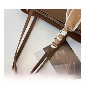 Detail of dark brown leather tote with decorative bear-print silk scarf on the handle