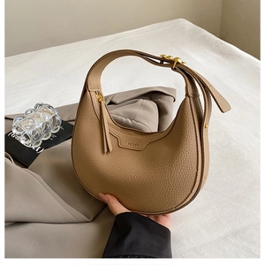 Macro detail of khaki litchi grain leather hobo bag with gold studs and tassel