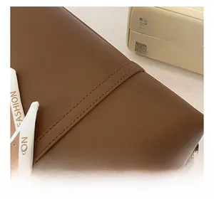 Detail of brown leather tote bag with precise stitching and silk scarf accessory