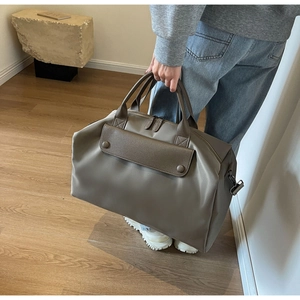 Detail of taupe travel tote with matte nylon texture and faux leather front pocket