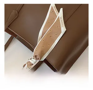 Detailed view of dark brown leather tote handle with a bear pattern silk scarf decoration