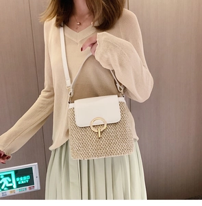 Détail du sac seau tissé avec rabat en cuir blanc et boucle dorée porté par un mannequin