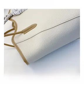 Close-up of pebble grain leather tote with brown trim and striped silk scarf detail