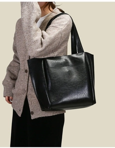 Dettaglio ravvicinato di una borsa tote in pelle nera morbida con texture liscia e capiente
