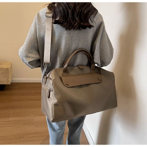 Macro detail of Earth-tone travel bag featuring premium nylon texture and leather flap