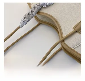 Detailed close-up of stitching craft on a cream leather tote bag with silk scarf handle