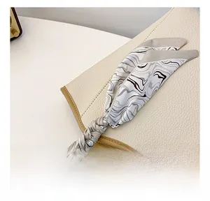 Detail of a marble pattern silk scarf wrapped around a leather tote handle