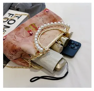 Detailed view of vintage floral embroidery handbag with pearl handle and metal chain strap