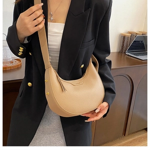 Detail of beige lychee grain leather crescent bag with gold rivets and wide strap