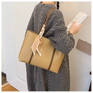 Detail of khaki tote bag featuring brown handles and fashion silk scarf decoration
