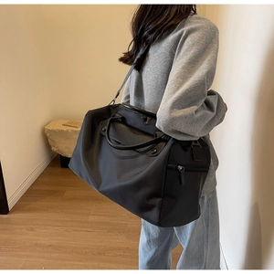 Detailed view of black nylon travel bag with leather accents on adjustable shoulder strap