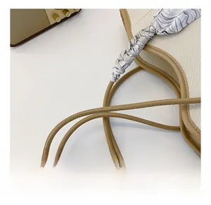 Detail of beige lychee leather tote bag featuring a decorative silk scarf on the strap