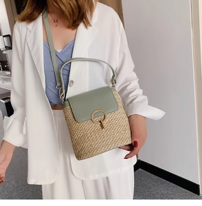 Détail du sac seau en paille tressée avec bordure en cuir vert et anneau en métal doré