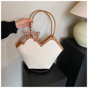 Detail of the V-shaped cream checkered tote bag with chic silk scarf on a pedestal