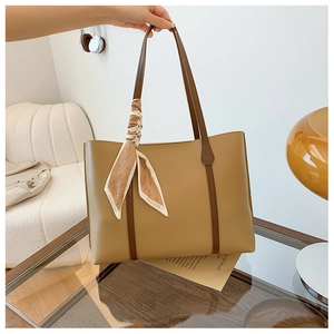 Detail of khaki tote bag with brown handles and a decorative fashion print silk scarf