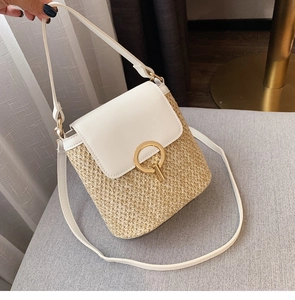 Détail du sac seau en paille avec bordure en cuir blanc et serrure dorée ronde