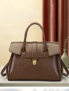 Close-up of vintage brown leather handbag with golden twist lock and adjustable strap